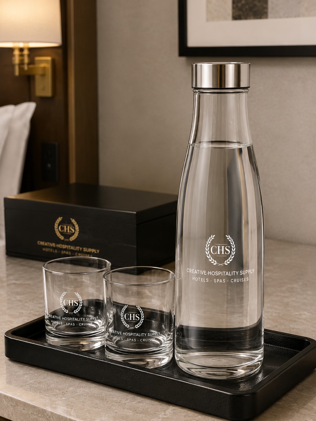 Glass bottle with two glasses and CHS logo on a tray